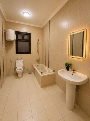 A bathroom with a toilet, bathtub, and sink, all with beige tiles. - Spacious 3-bedroom apartment in casa Beverly hills sodic Giza Governorate (Giza Governorate)