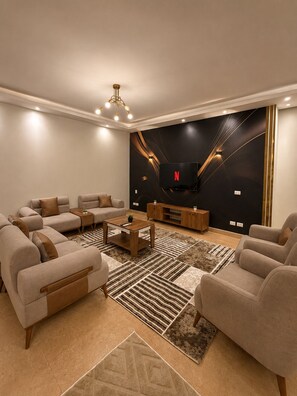 A modern living room with a sectional sofa, a coffee table, and a flat-screen TV mounted on a black wall. - Spacious 3-bedroom apartment in casa Beverly hills sodic Giza Governorate (Giza Governorate)