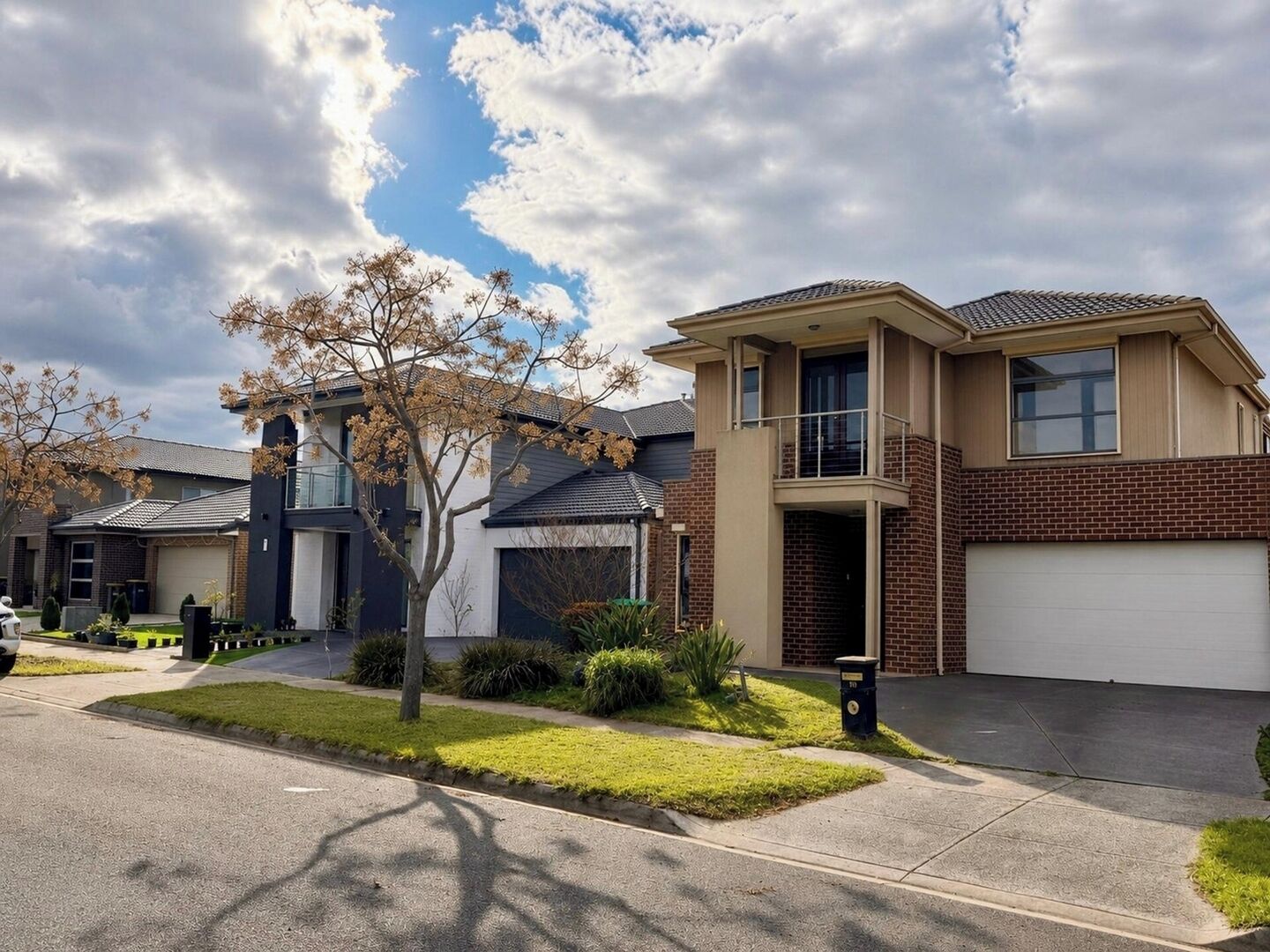 A two-story residential house with a garage, a tree in the front yard, and a clear sky.