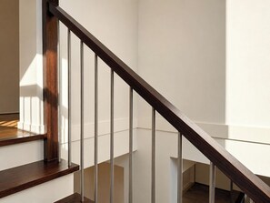 A wooden staircase with a glass balustrade, leading to a landing with a white wall and a wooden floor. - 4BR Point Cook Home | Sleeps 8 | Free Parking (Point Cook)