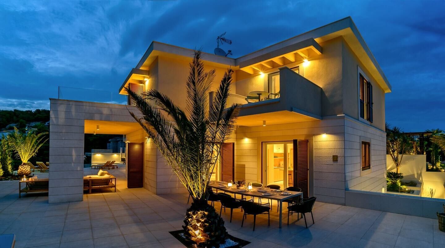 A modern two-story house with a dining area and outdoor seating.