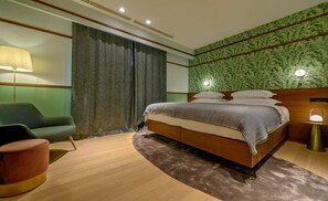 A modern bedroom with a bed, a green armchair, a round ottoman, and a patterned wall. - Villa Rijeka, Private villa with pool, Hvar Island (Hvar)