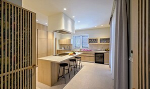 A modern kitchen with a central island, bar stools, and a built-in stove. - Villa Rijeka, Private villa with pool, Hvar Island (Hvar)