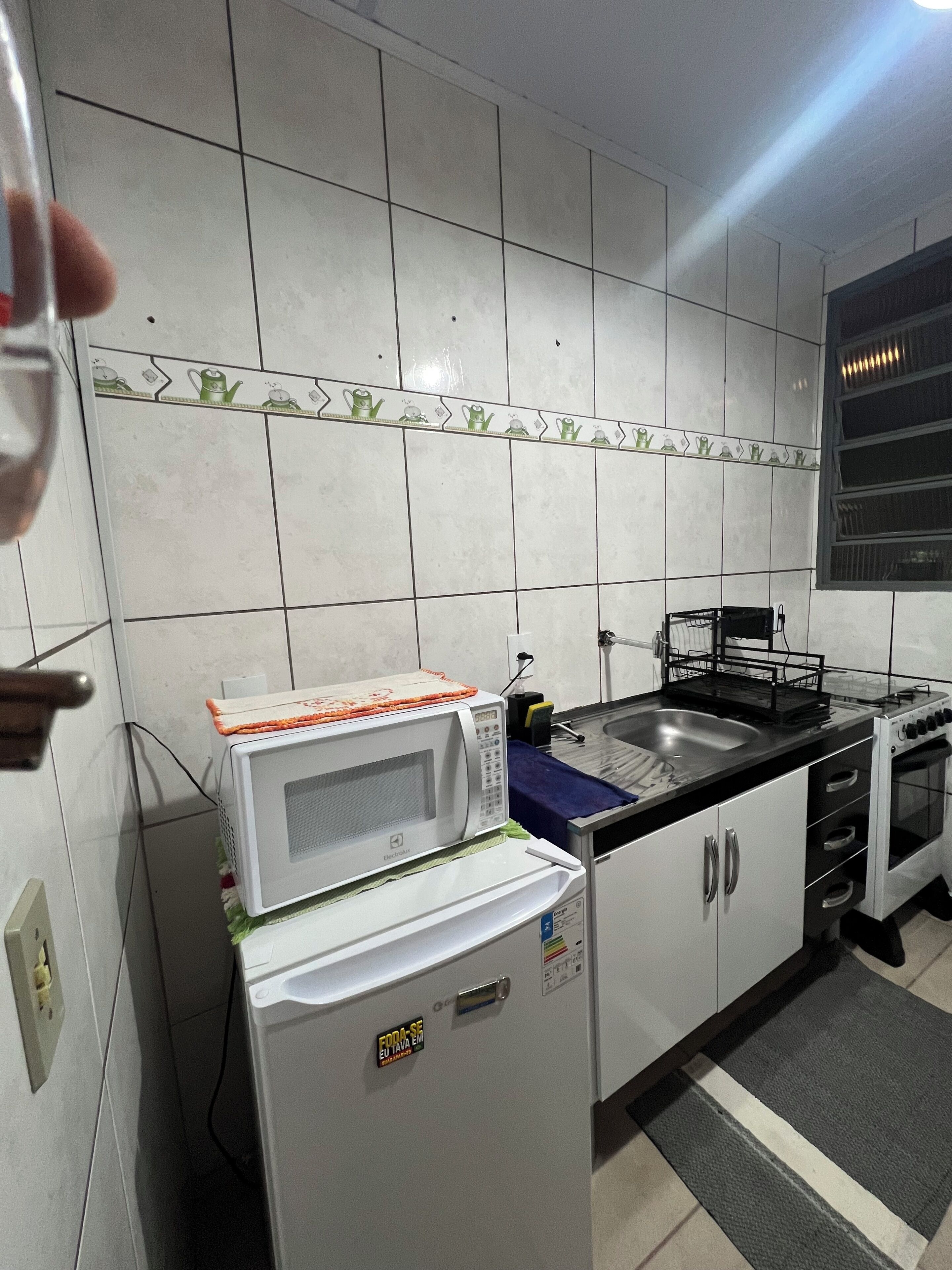 Una cocina con armarios blancos, un microondas, un lavaplatos y una estufa.