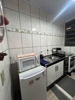 Una cocina con armarios blancos, un microondas, un lavaplatos y una estufa.
