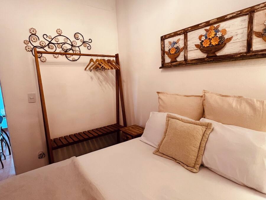 A bedroom with a bed, a wooden headboard, a wall-mounted art piece, and a hanging light fixture.
