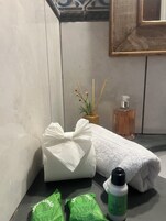 Un baño con una toalla, una botella de jabón para manos y una bolsita verde en la encimera.