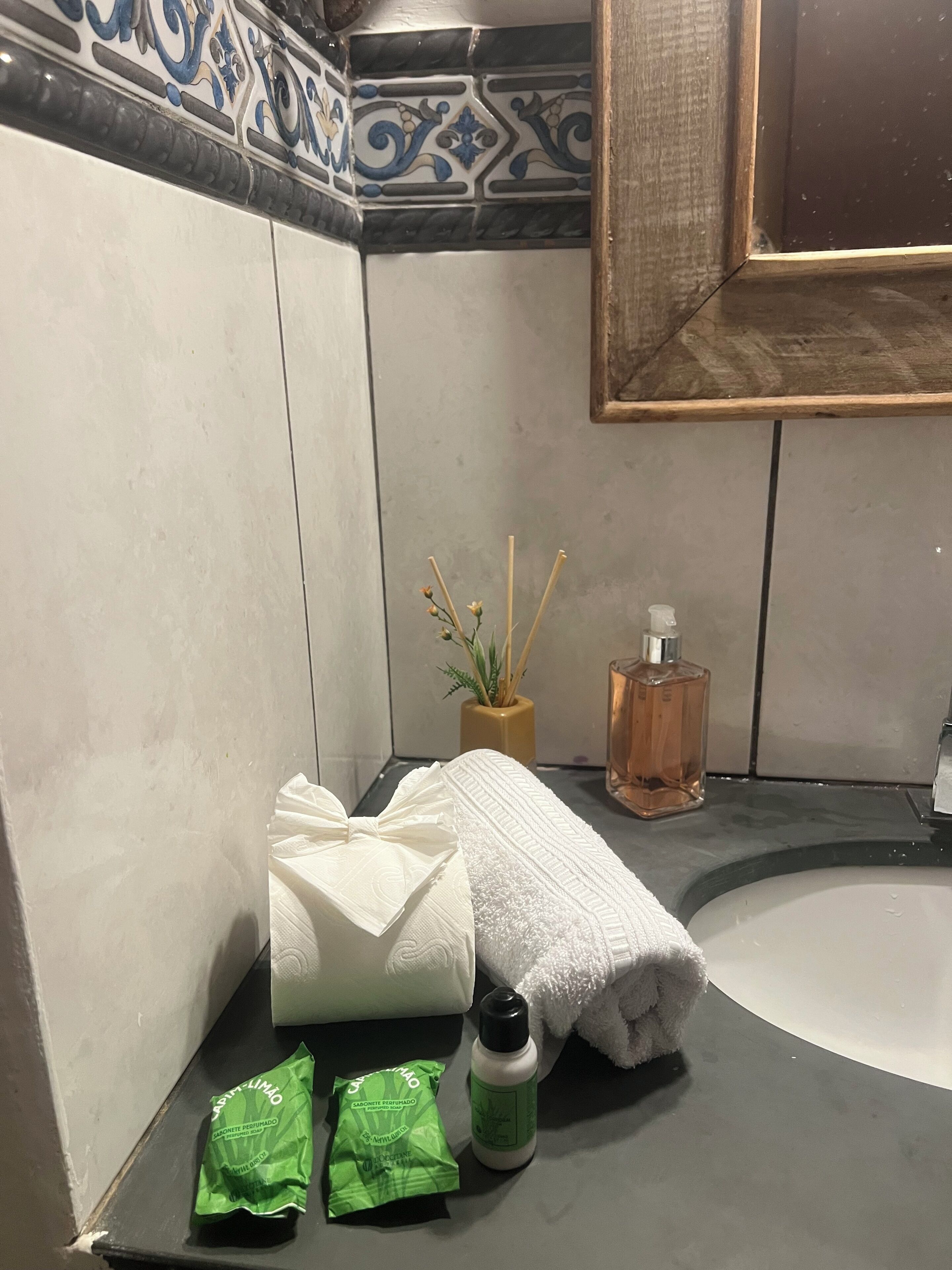Une salle de bain avec une baignoire blanche, un lavabo, un flacon de savon liquide et deux petits sachets de savon verts.