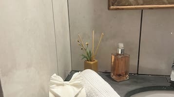 Une salle de bain avec une baignoire blanche, un lavabo, un flacon de savon liquide et deux petits sachets de savon verts.