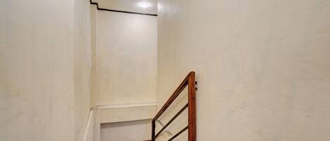 A narrow stairway with wooden handrails and a white wall.