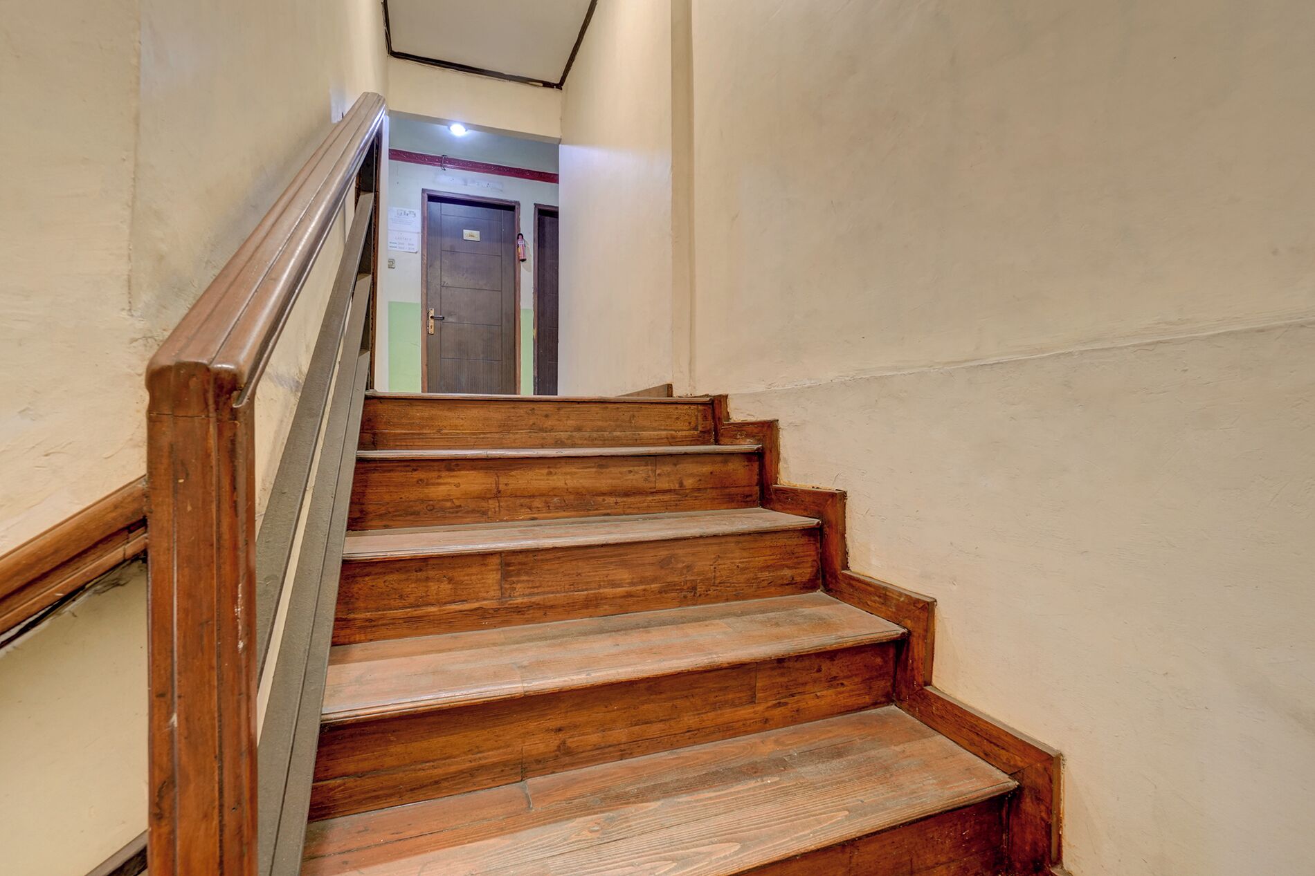 A wooden staircase with a handrail leading to a door at the top.