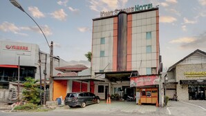 A hotel with a prominent sign, a Yamaha dealership, and a small food stall.