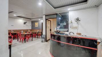 Interior de restaurante com balcão, cadeiras vermelhas e piso de azulejos.
