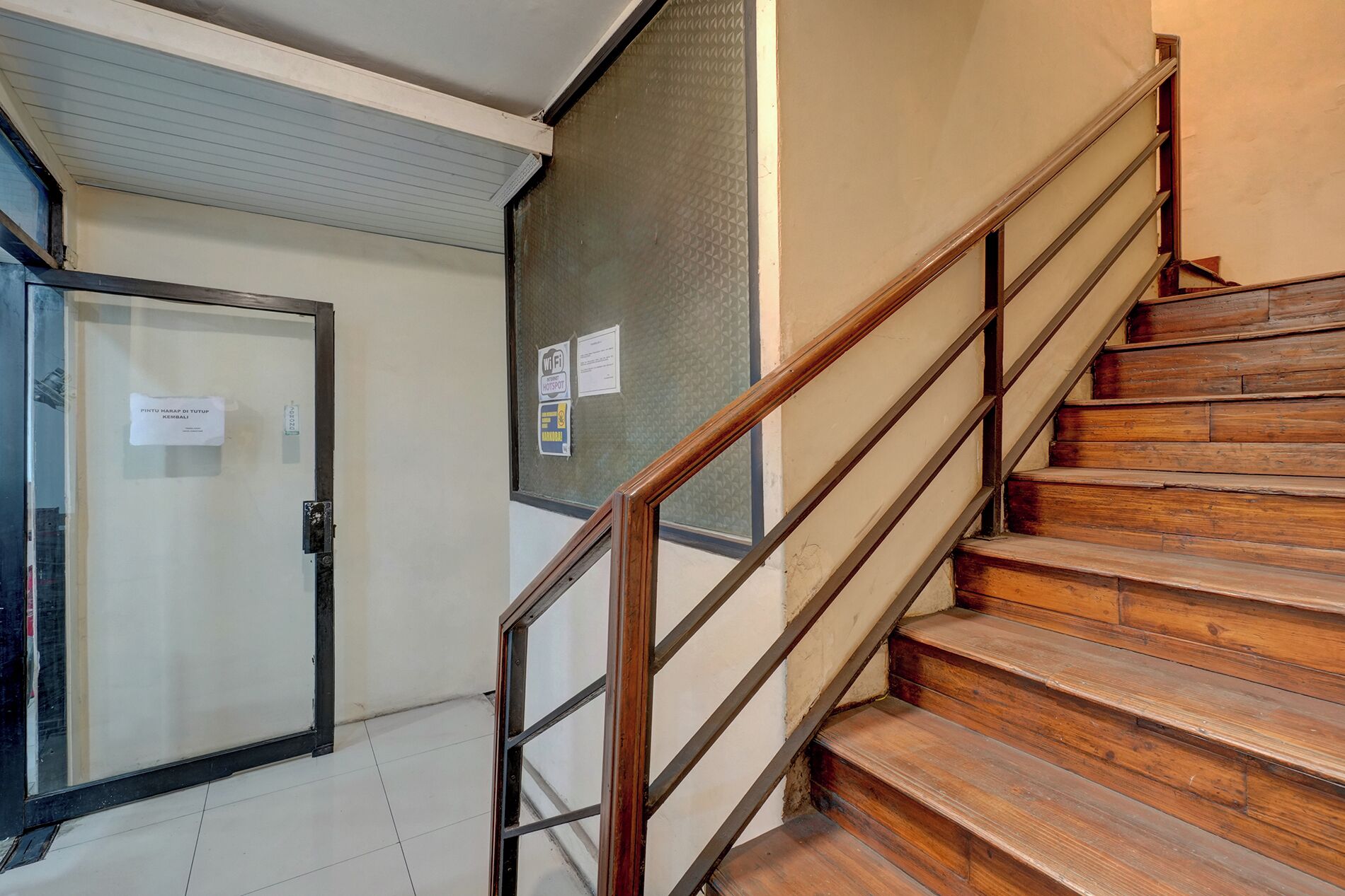 A staircase with wooden steps and metal railings, leading to a room with a closed door and a window.
