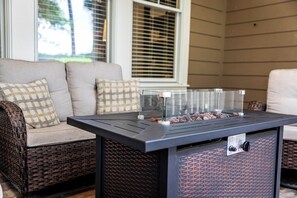 Ein Patio mit einem Metalltisch, Korbmöbeln und einem Fenster mit Rollläden.