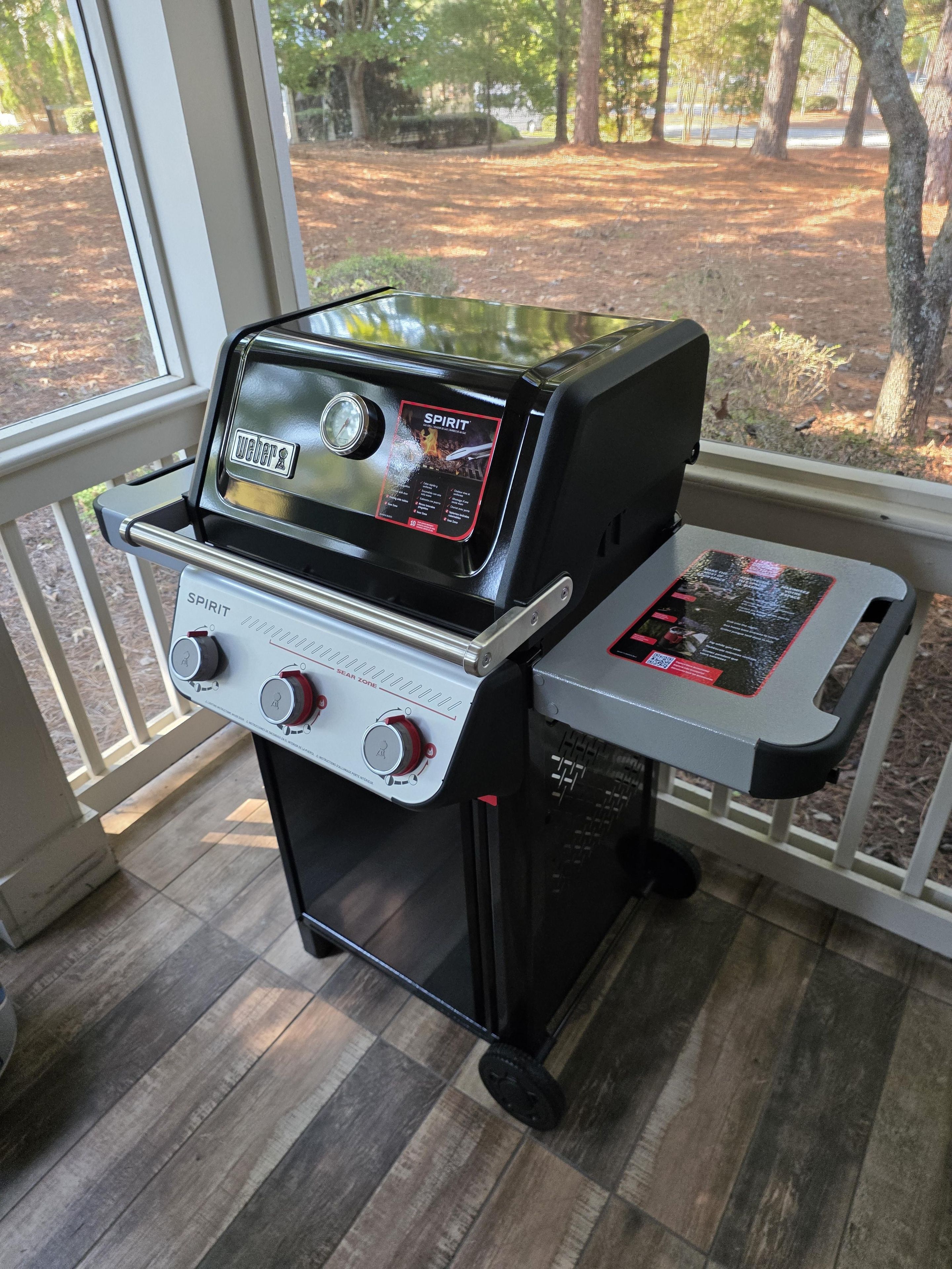 A Weber Spirit portable grill with a digital display, control knobs, and a side table.