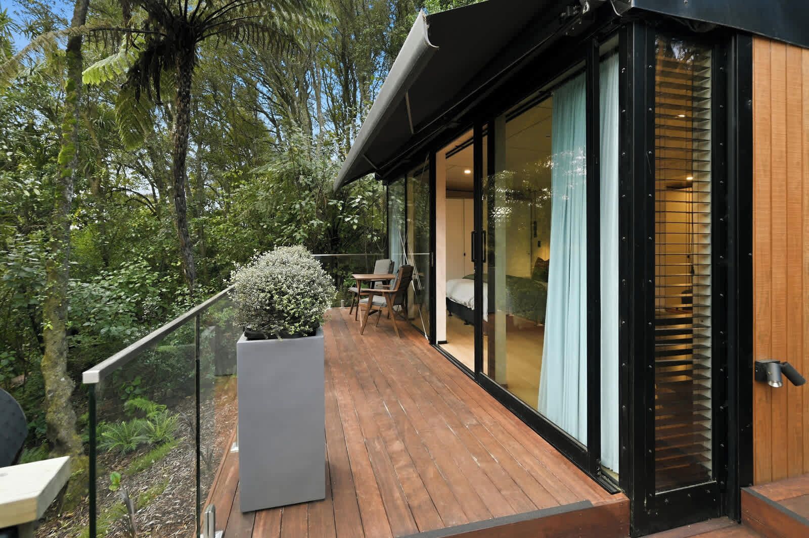 Ein modernes Haus mit einer Holterrasse, einem großen Schiebeglastür und einem Blumentopf.