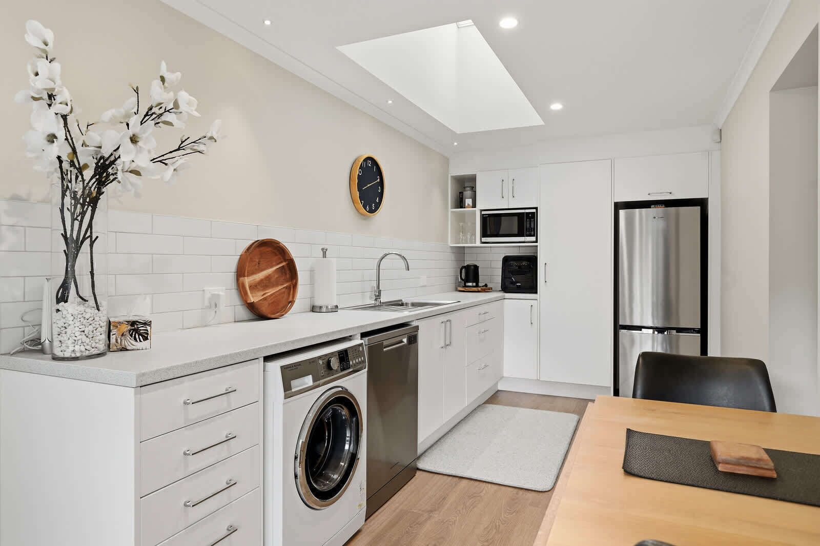 A modern kitchen with a dishwasher, washing machine, microwave, and refrigerator.