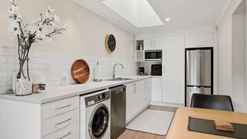 A modern kitchen with a dishwasher, washing machine, microwave, and refrigerator.