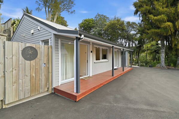 A single-story building with a covered porch, a wooden fence, and a paved driveway.