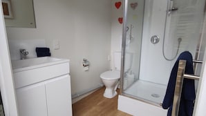 A bathroom with a white sink, toilet, and glass-enclosed shower.
