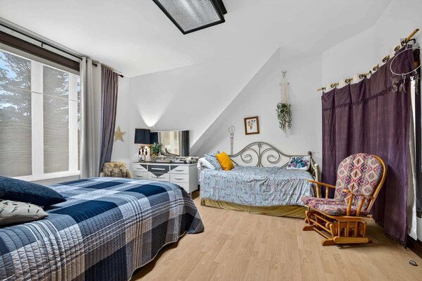 Une chambre à coucher avec un lit, une chaise, une commode et une fenêtre.