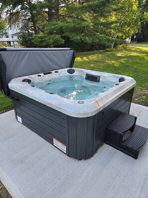Un bain à remous doté d’une couverture, d’un marchepied et d’une étiquette d’avertissement sur le côté.
