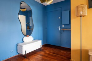 Ein Badezimmer mit einer weißen Ablage, einem großen Spiegel, einer Tür und einer Wandleuchte.
