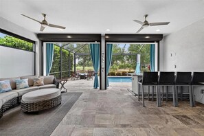 A covered outdoor area with a sofa, chairs, a pool, and ceiling fans. - 3 bed house in Esplanade Lakewood Ranch Bradenton with private POOL and GOLF (Bradenton)