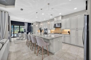 A modern kitchen with a central island, bar stools, and a large refrigerator. - 3 bed house in Esplanade Lakewood Ranch Bradenton with private POOL and GOLF (Bradenton)