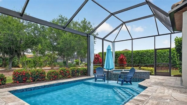 A covered swimming pool with a patio area, surrounded by landscaped gardens and trees. - 3 bed house in Esplanade Lakewood Ranch Bradenton with private POOL and GOLF (Bradenton)