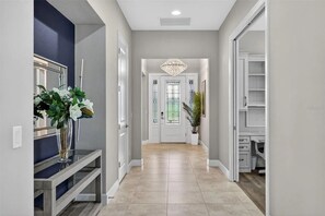 A hallway with a chandelier, a potted plant, and a door leading to a room. - 3 bed house in Esplanade Lakewood Ranch Bradenton with private POOL and GOLF (Bradenton)
