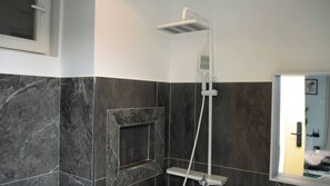 A shower with a handheld head, a wall-mounted control panel, and a rectangular niche in the wall.