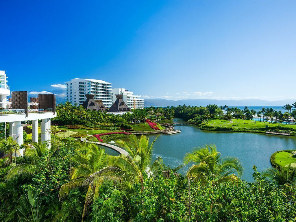 Ein Resort mit See, Palmen und modernen Gebäuden.