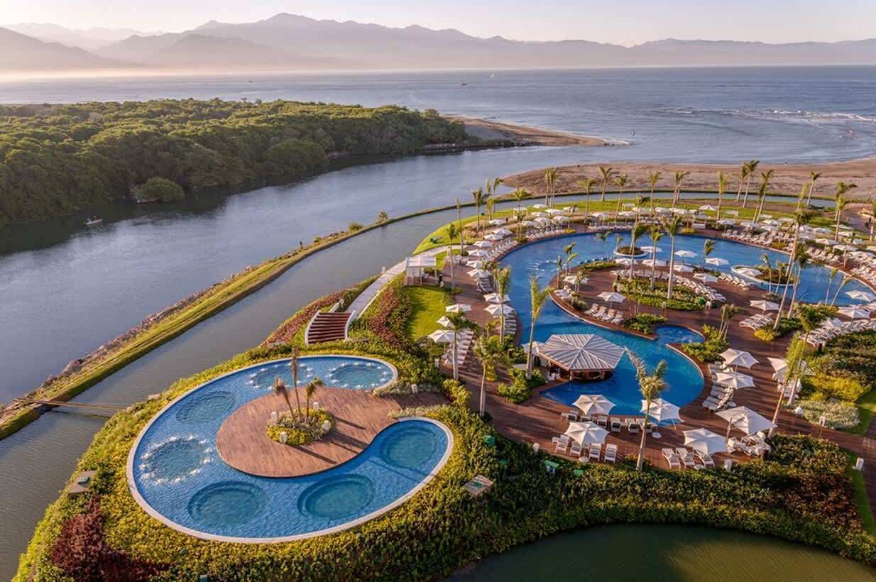 Un complexe hôtelier doté d’une grande piscine centrale, de plusieurs petites piscines et d’une plage.