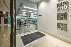 Ein modernes Fitnessstudio mit Glastüren, Laufbändern und Wanduhren.