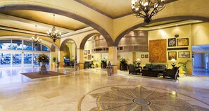 A spacious lobby with a central fountain, seating area, and a large window providing a view of the outdoors. - Beach Resort Del Arco with Breathtaking Oceanviews (Cabo San Lucas)
