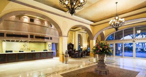 En hotellobby med en receptionsdisk, ett område för måltider och ett stort fönster med utsikt.