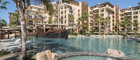 Un resort con piscina, palmeras y una estructura con forma de barco.