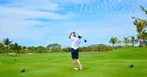 Ein Golfplatz mit blauem Himmel und Palmen.