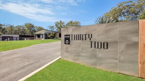 A modern building with a large sign reading 'THIRTY TWO' and a parking area with a covered carport. - Tranquility On Invermay (Tomerong)