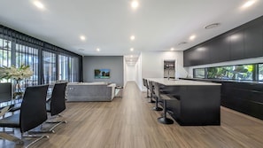 A modern kitchen with a central island, bar stools, and a dining area with a sofa and chairs. - Tranquility On Invermay (Tomerong)