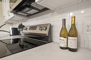 A kitchen with a stainless steel oven, two wine bottles on the counter, and a knife block. - Stunning Designer Home Minutes to NRG, Medical Center & Downtown Sleeps 9 (Houston)