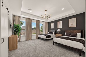 A modern bedroom with two beds, a large window, and a ceiling light fixture. - Stunning Designer Home Minutes to NRG, Medical Center & Downtown Sleeps 9 (Houston)