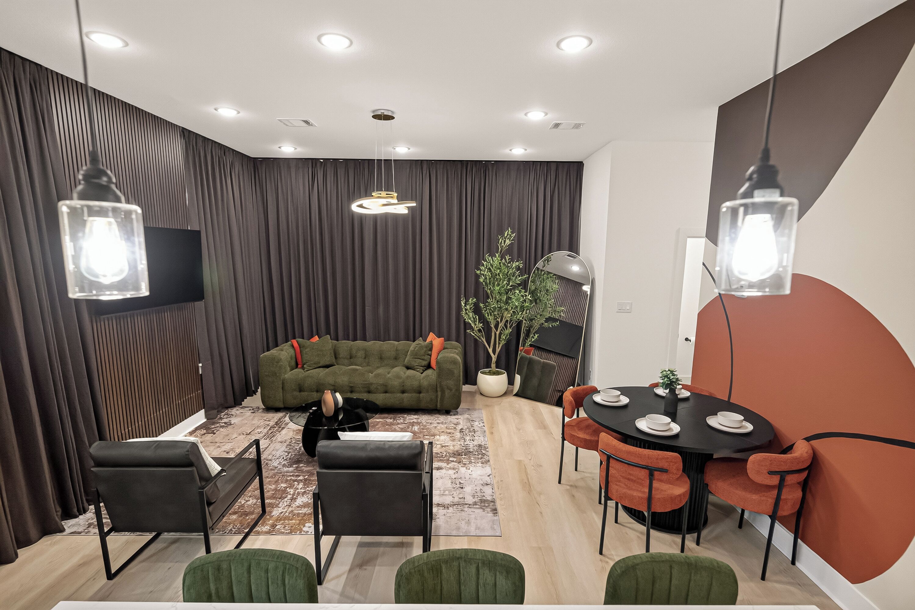 A modern living room with a sofa, a dining table with chairs, and a potted plant.