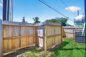 A fenced outdoor area with a grassy ground, a metal structure, and a clear sky. - Stunning Designer Home Minutes to NRG, Medical Center & Downtown Sleeps 9 (Houston)