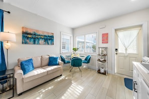 Ein modernes Wohnzimmer mit einem beigefarbenen Sofa, blauen Kissen, einem Couchtisch und einem Gemälde an der Wand.