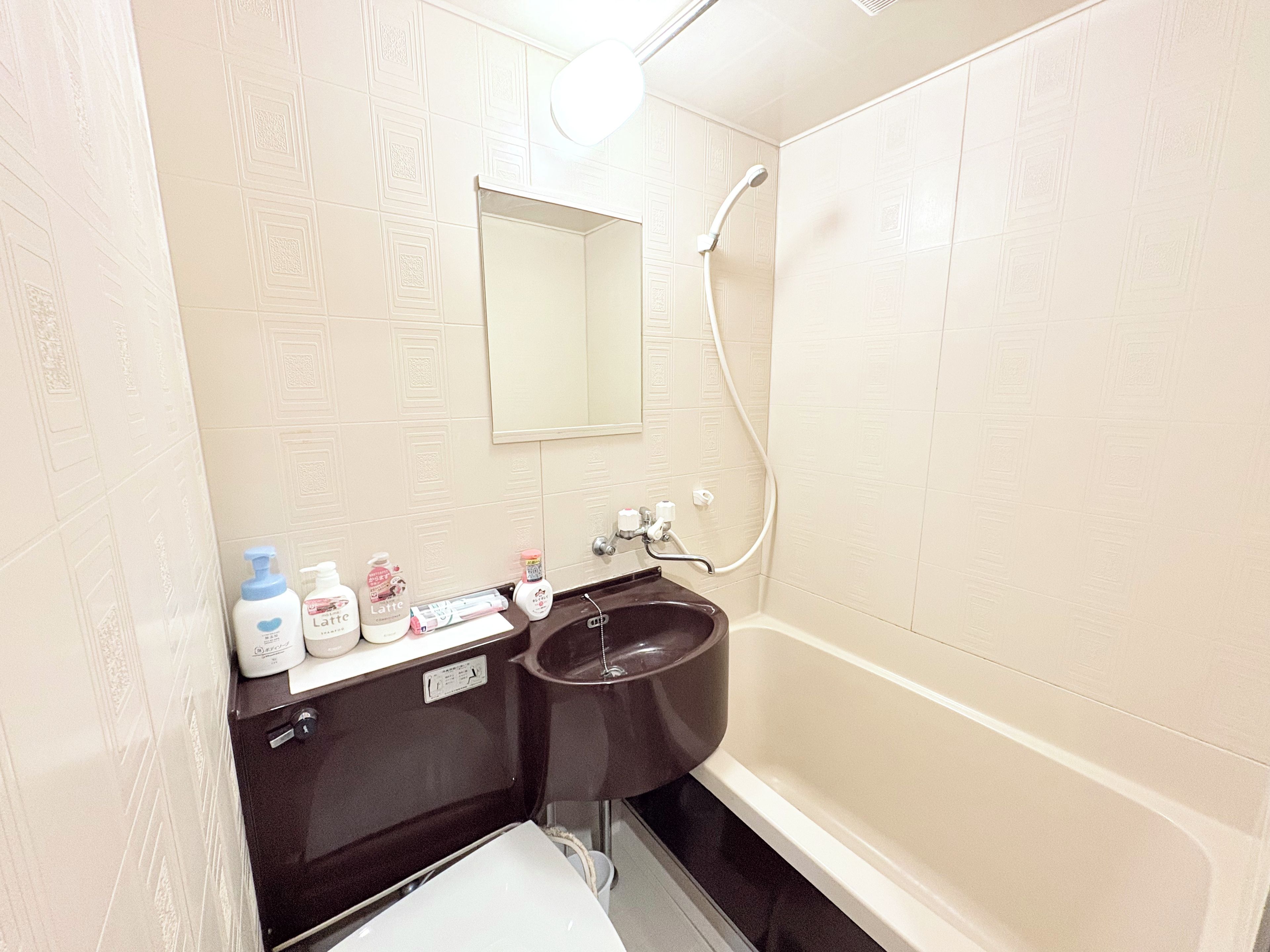 Une salle de bain avec une baignoire, un lavabo et un miroir. On trouve des articles de toilette sur le comptoir du lavabo.