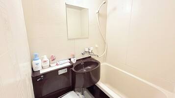 A bathroom with a bathtub, a sink, and a mirror. There are toiletries on the sink counter.
