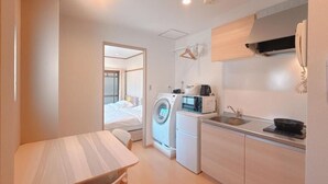 Ein kleines Hotelzimmer mit Küchenzeile, Waschmaschine und einem Bett.